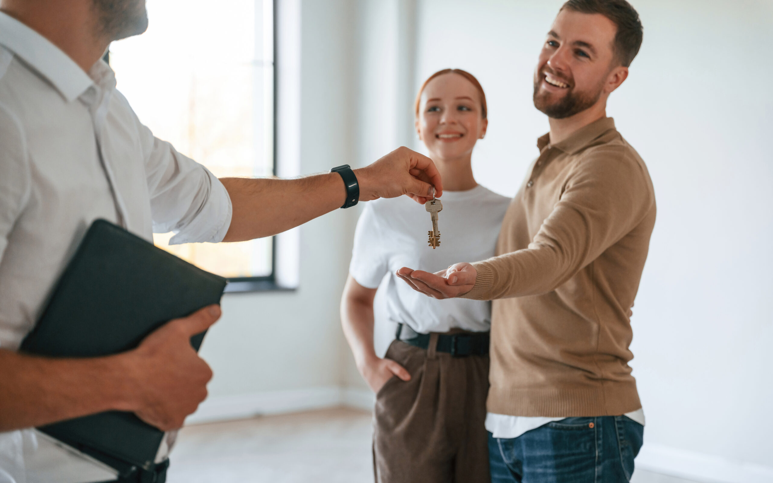 Giving the keys. Realtor shows an apartment to a young couple